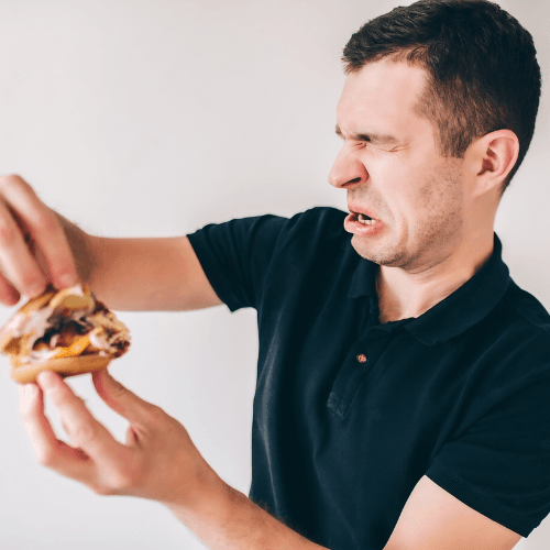 Person eating a burger and being disgusted